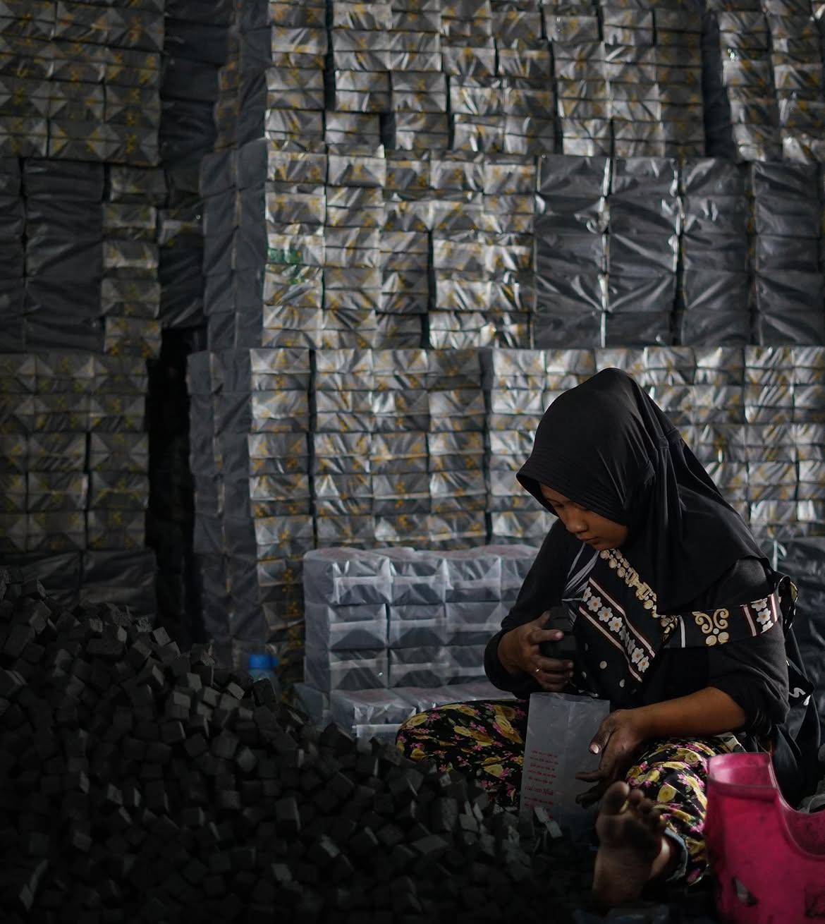 Worker packing finished COCOPREM coconut charcoal briquettes